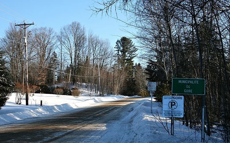 Chemin enneigé à l'entrée de la municipalité de Gore, bordé de poteaux électriques