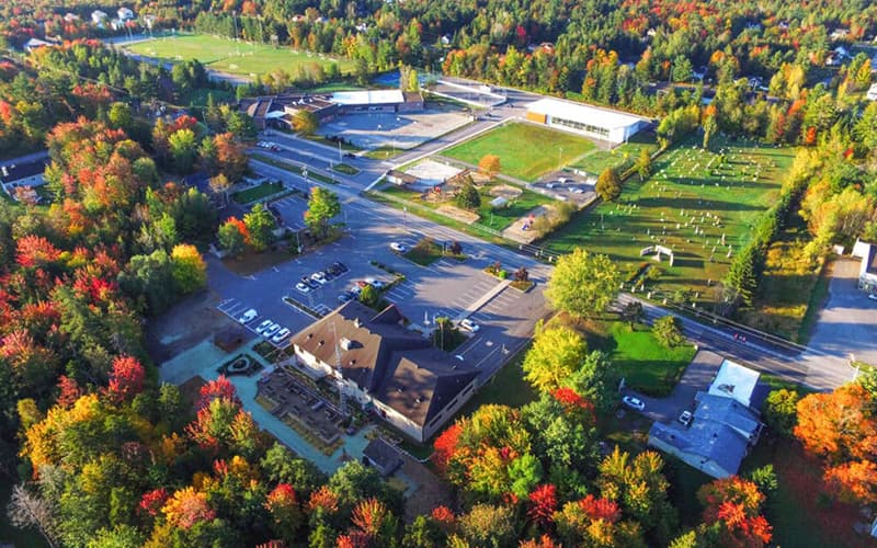 Vue aérienne de bâtiments et de terrains sportifs entourés d'arbres aux couleurs d'automne