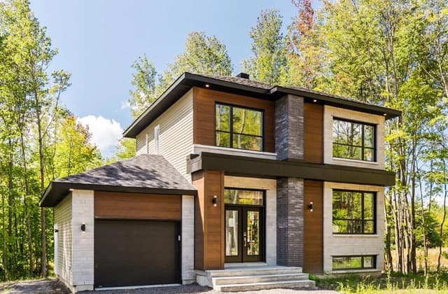 Maison neuve de deux étages entourée d'arbres