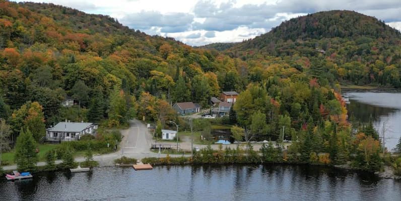 Village en bordure d'un lac, entouré de collines boisées en automne