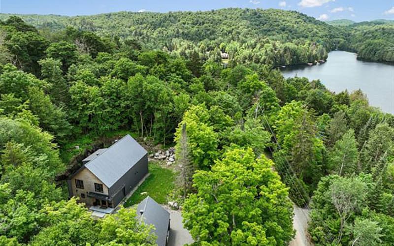 Vue aérienne d'une maison moderne en forêt, près d'un lac